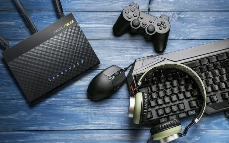 Modern PC Keyboard, Mouse, Game Pad, Router, and Headphones on Wooden Table