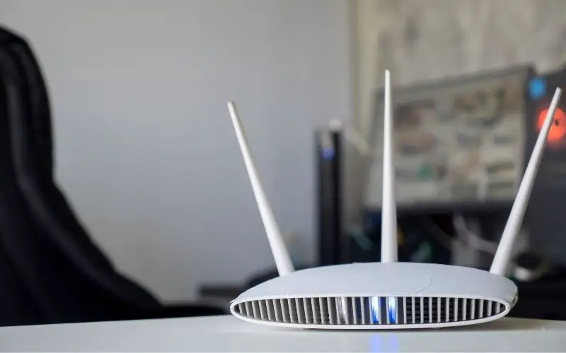Close up of a wireless router on table at home with desktop computer background