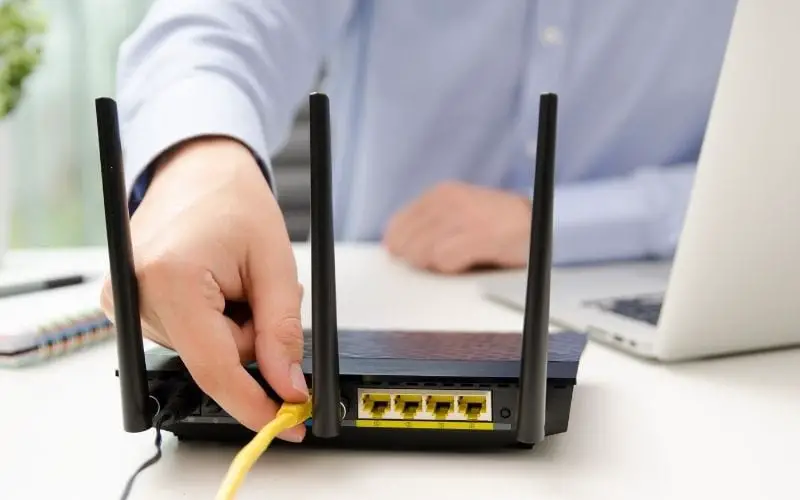 Man plugs Ethernet cable into the router